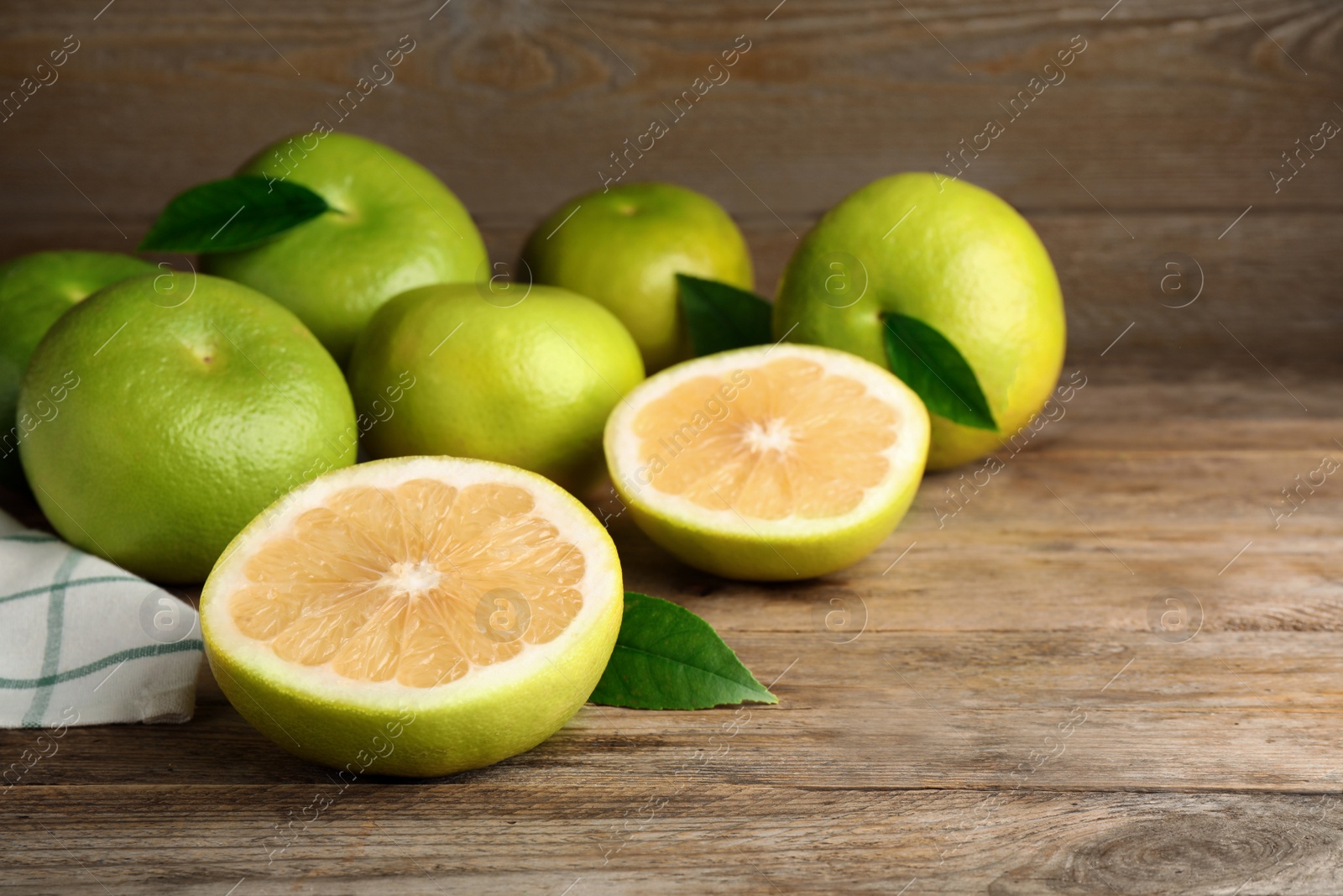 Photo of Whole and cut sweetie fruits on wooden table, space for text