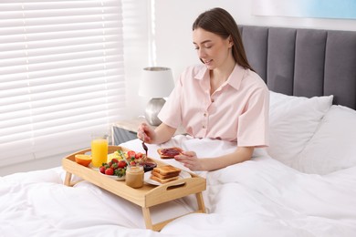 Photo of Beautiful woman having tasty breakfast in bed at home