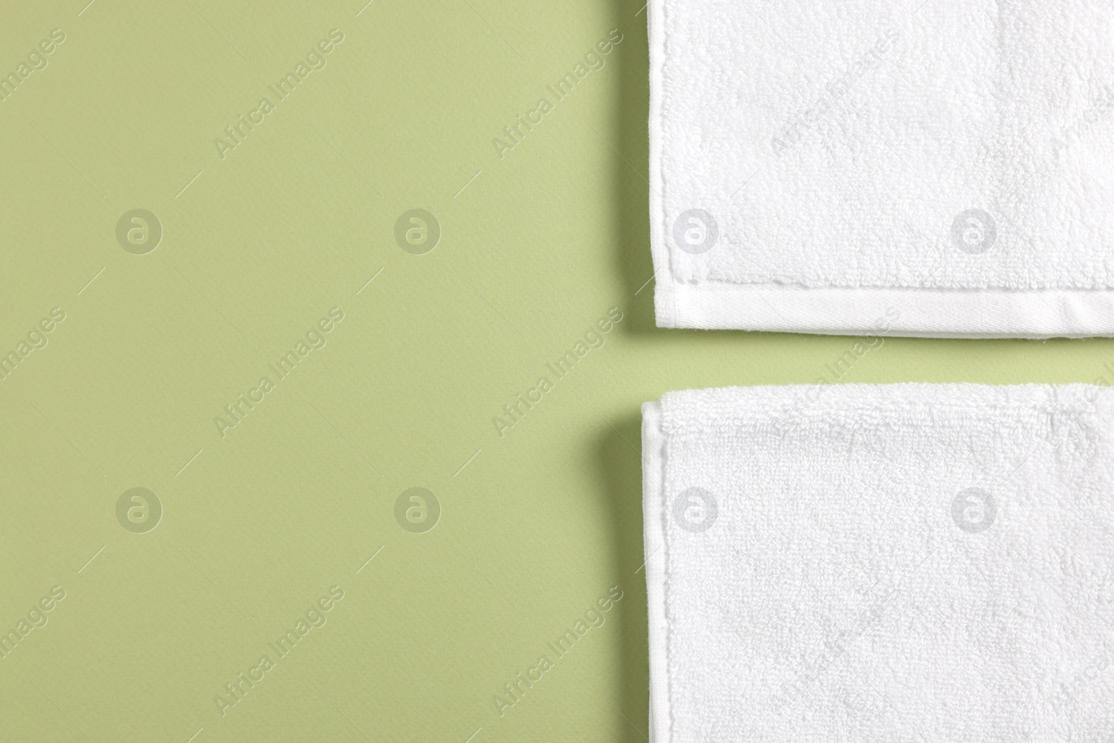 Photo of Soft folded white towels on green background, flat lay. Space for text