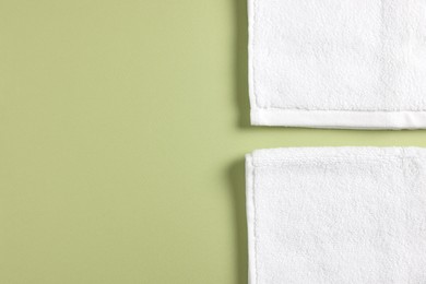 Soft folded white towels on green background, flat lay. Space for text