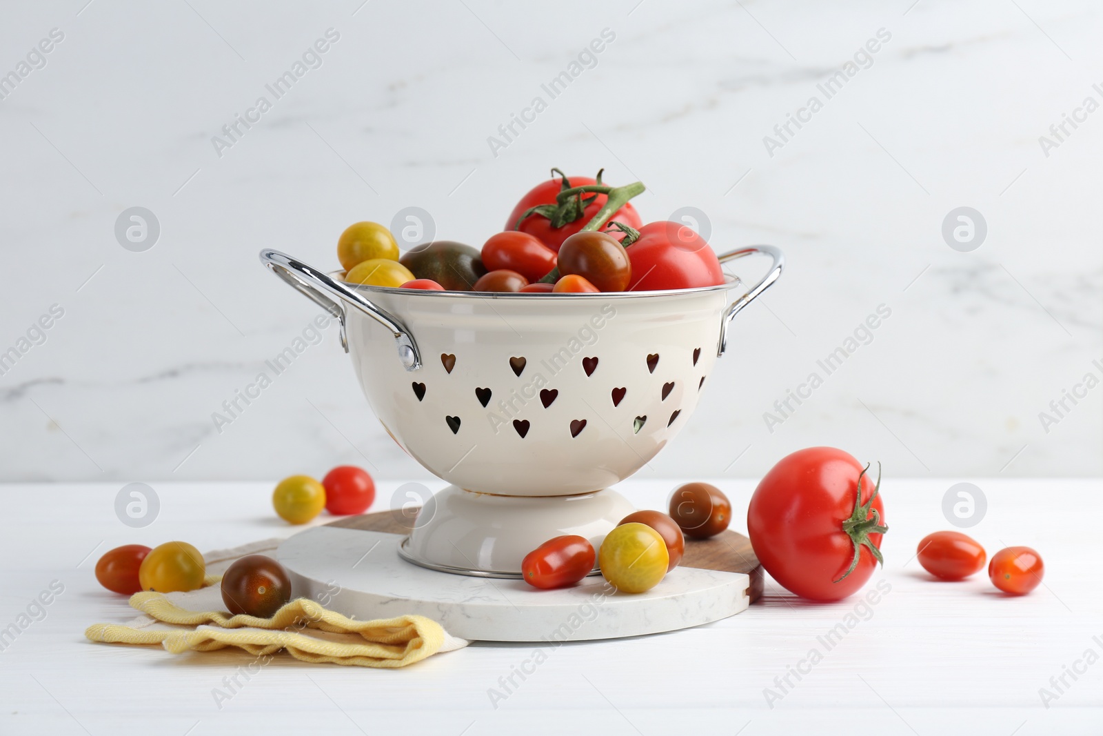 Photo of Metal colander with fresh tomatoes on white wooden table