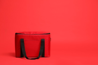 Photo of Modern large thermo bag on red background. Space for text
