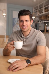 Man with cup of coffee at cafe in morning