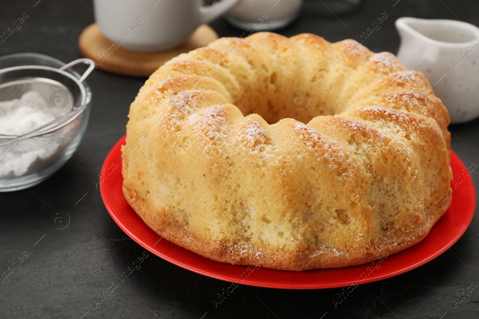 Photo of Delicious freshly baked sponge cake on black table, closeup