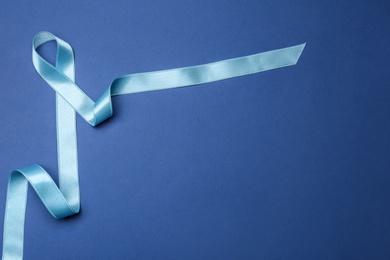 Photo of Light blue awareness ribbon on color background, top view with space for text. Symbol of social and medical issues