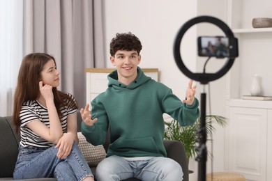 Photo of Smiling teenage bloggers talking while streaming at home