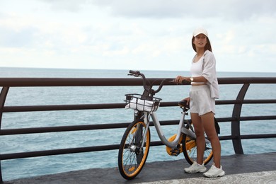 Photo of Beautiful young woman with bicycle near sea. Space for text