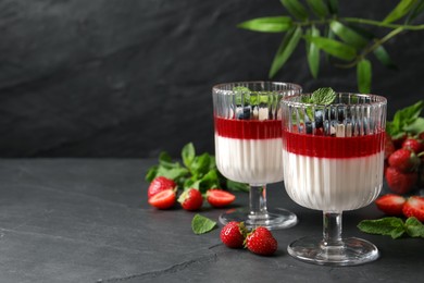 Photo of Delicious panna cotta with fruit coulis and fresh berries on dark grey table. Space for text