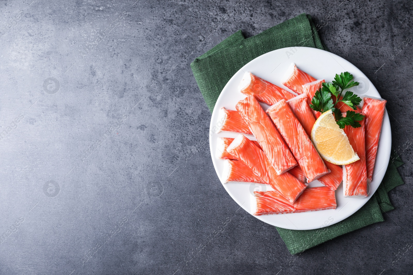 Photo of Fresh crab sticks with lemon on grey table, top view. Space for text