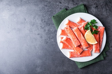 Fresh crab sticks with lemon on grey table, top view. Space for text