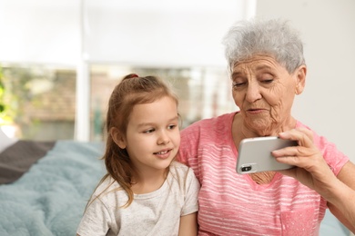 Cute girl and her grandmother taking selfie  at home