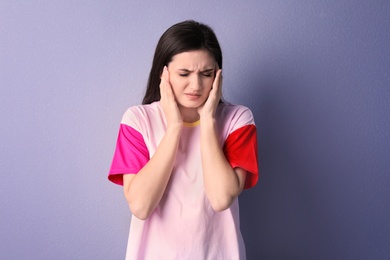 Photo of Young woman suffering from headache on color background