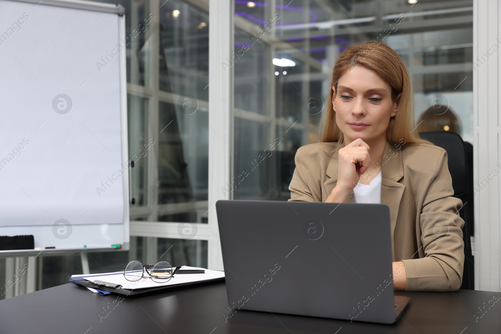 Photo of Woman working on laptop at black desk in office