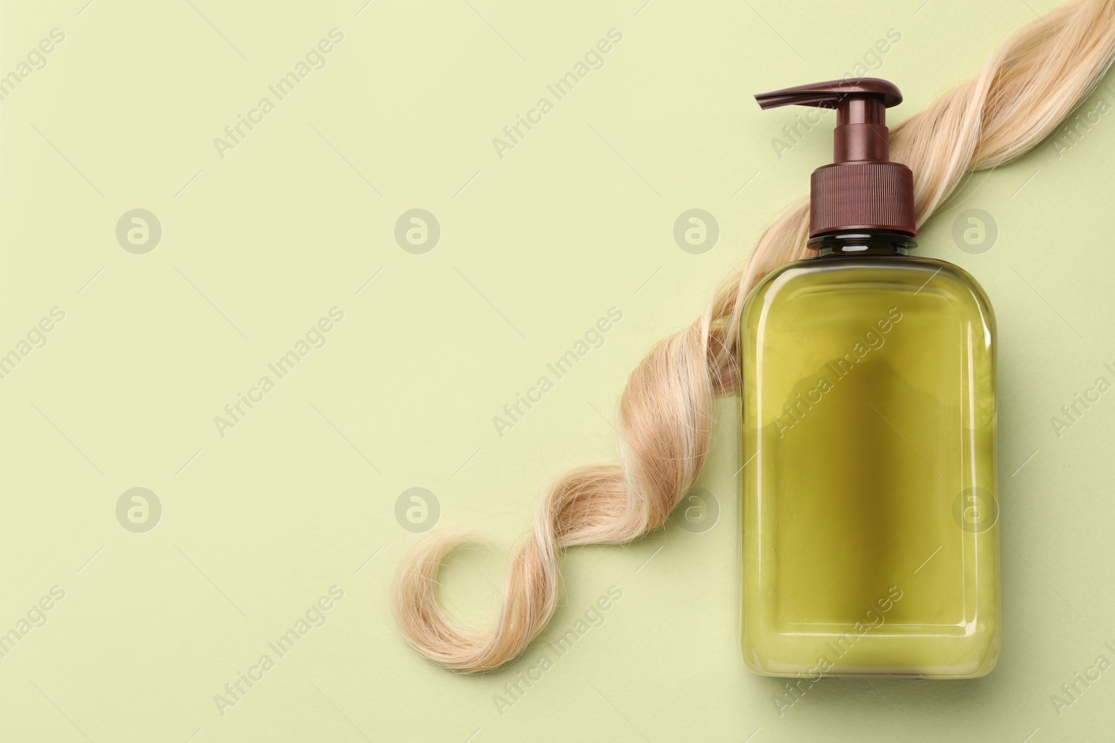 Photo of Lock of hair and shampoo bottle on olive background, flat lay. Space for text