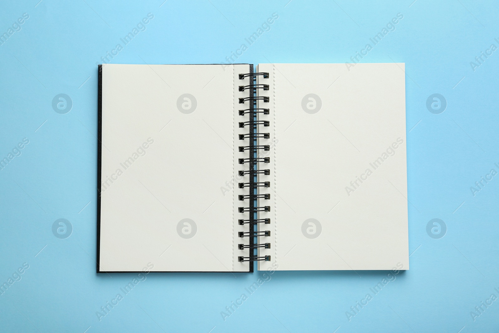 Photo of Open notebook on light blue background, top view