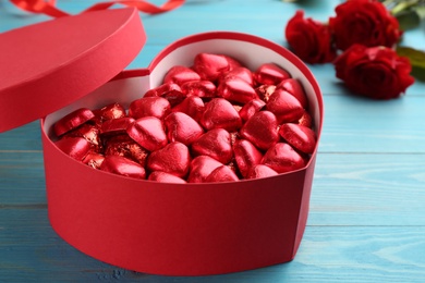 Heart shaped chocolate candies in gift box on blue wooden table. Valentines's day celebration