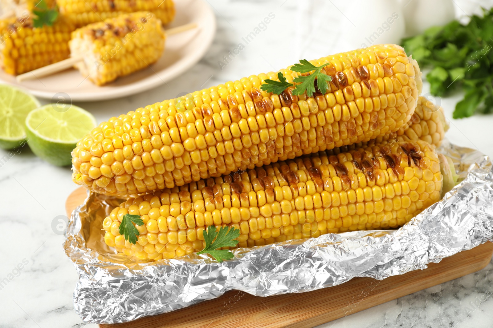 Photo of Tasty grilled corn on white marble table