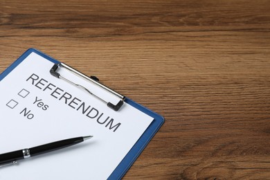 Referendum ballot with clipboard and pen on wooden table. Space for text