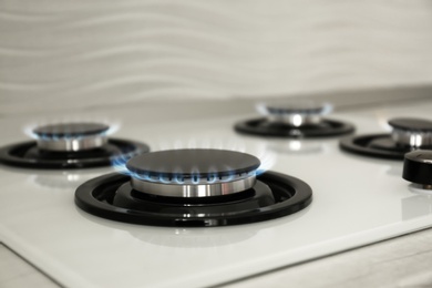 Photo of Gas burners with blue flame on modern stove, closeup. Space for text