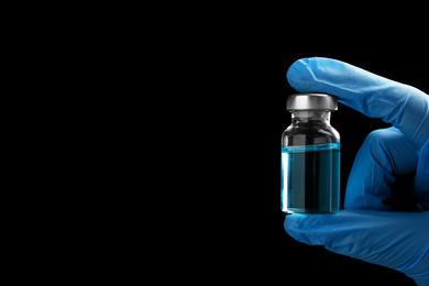 Photo of Doctor holding vial with medication on black background, closeup view and space for text. Vaccination and immunization