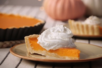 Piece of fresh homemade pumpkin pie with whipped cream on table