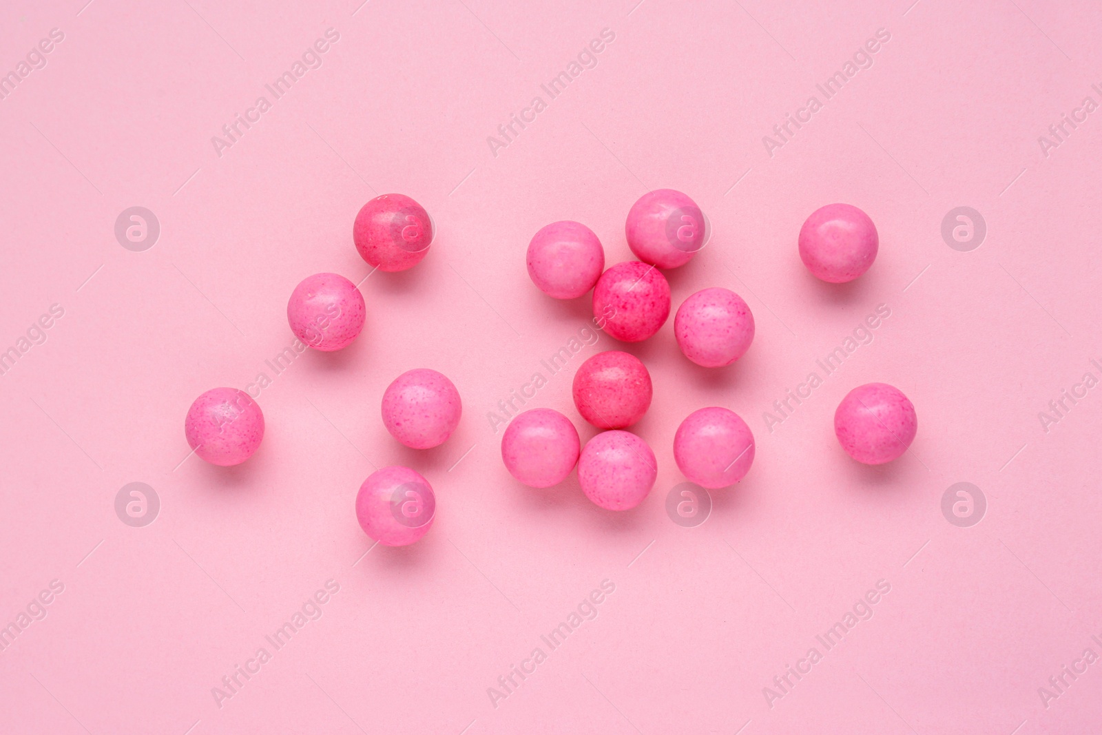 Photo of Many bright chewy gumballs on pink background, flat lay