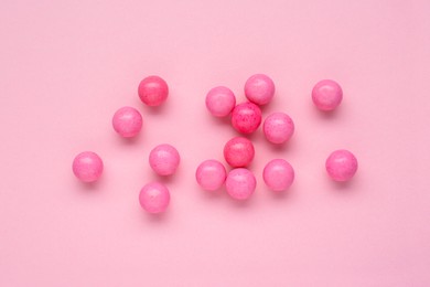 Photo of Many bright chewy gumballs on pink background, flat lay