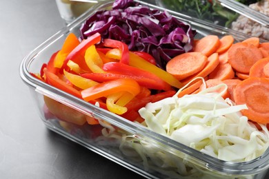 Tasty vegetables in glass container on grey table, closeup