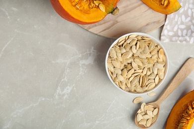 Photo of Flat lay composition with raw pumpkin seeds on light grey marble table. Space for text