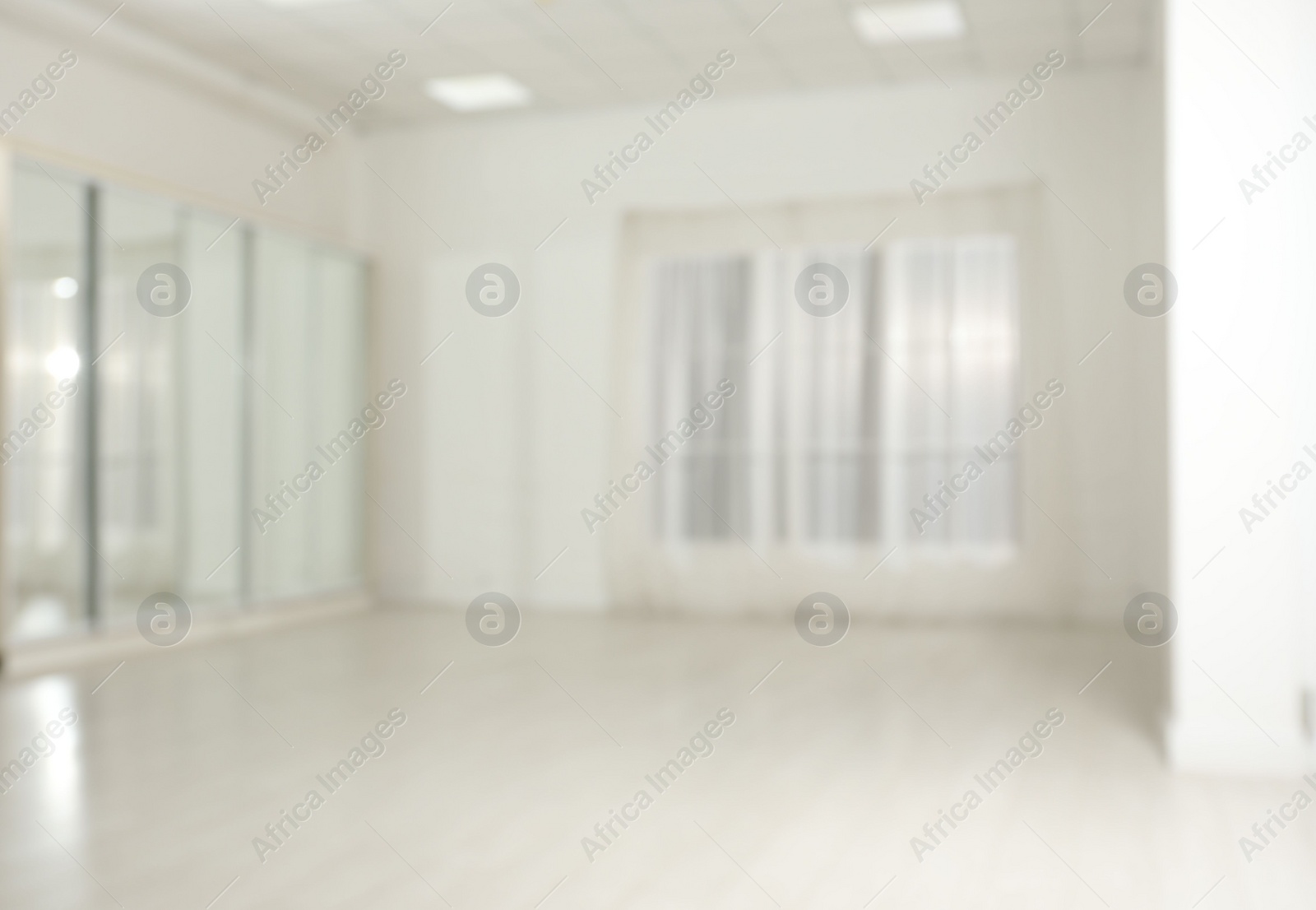 Photo of Empty room with white walls and large window, blurred view