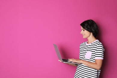 Photo of Young woman with modern laptop on color background