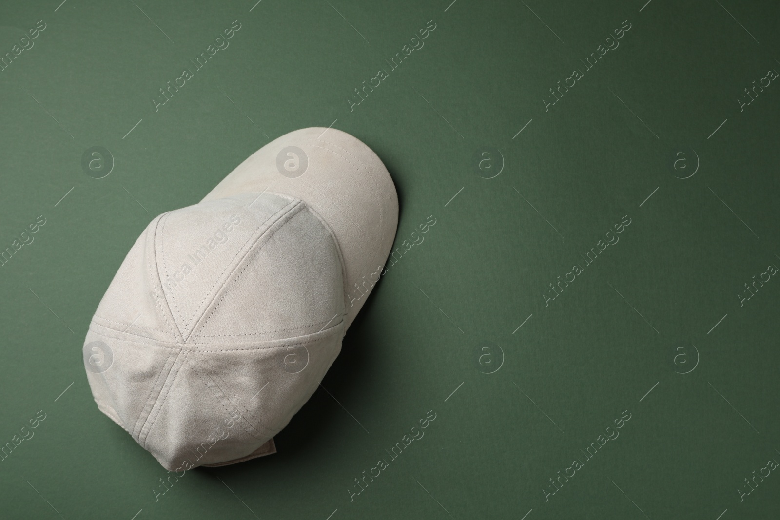 Photo of Stylish beige baseball cap on dark green background, top view. Space for text