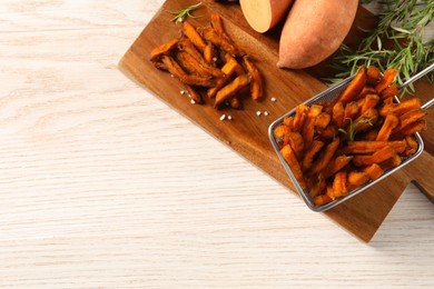 Photo of Sweet potato fries and rosemary on wooden table, top view. Space for text