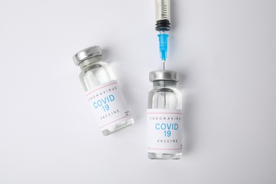 Photo of Filling syringe with coronavirus vaccine on white  background, flat lay