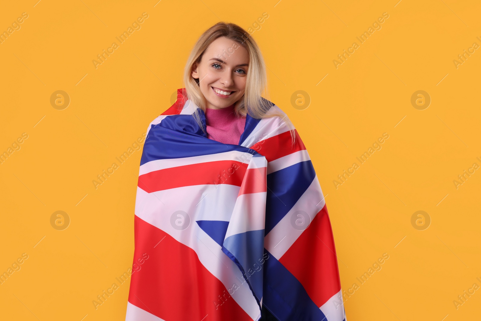 Photo of Happy woman with flag of United Kingdom on orange background