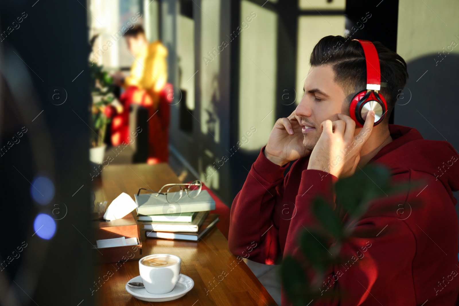 Photo of Man listening to audiobook at table in cafe