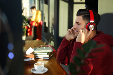 Photo of Man listening to audiobook at table in cafe