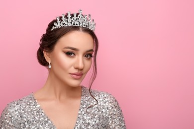 Beautiful young woman wearing luxurious tiara on pink background, space for text