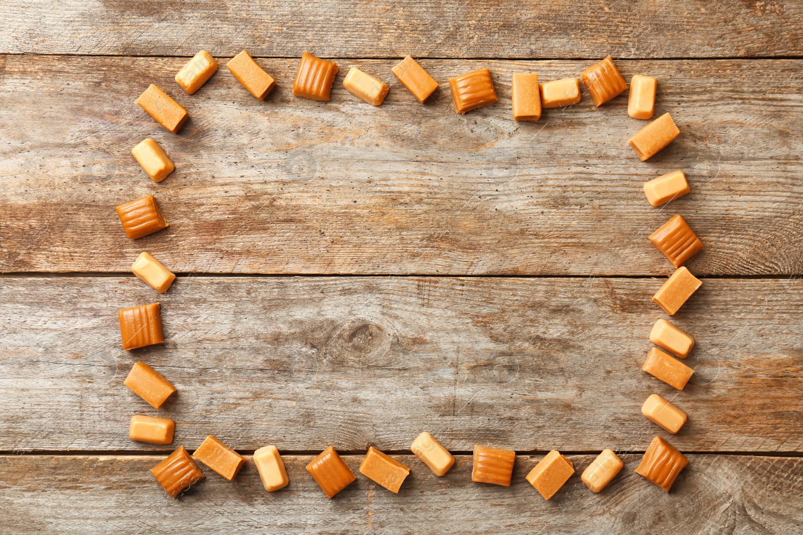 Photo of Delicious caramel candies on wooden background