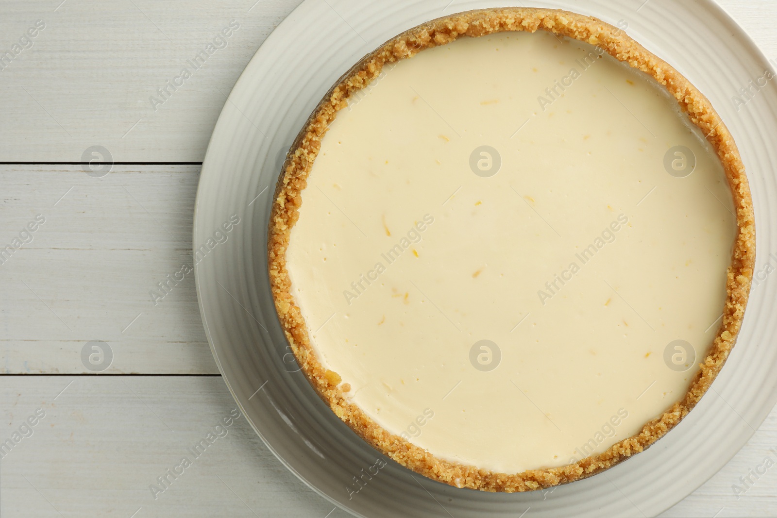 Photo of Tasty vegan tofu cheesecake on white wooden table, top view. Space for text