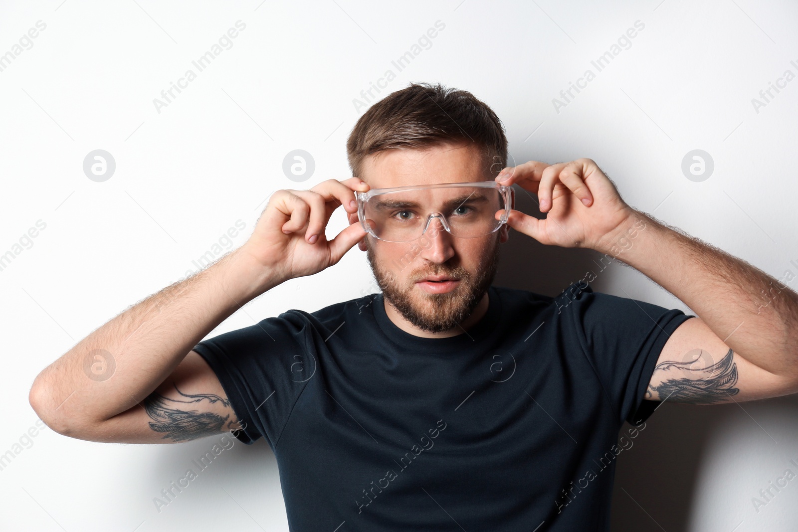 Photo of Young working man in protective glasses on light background