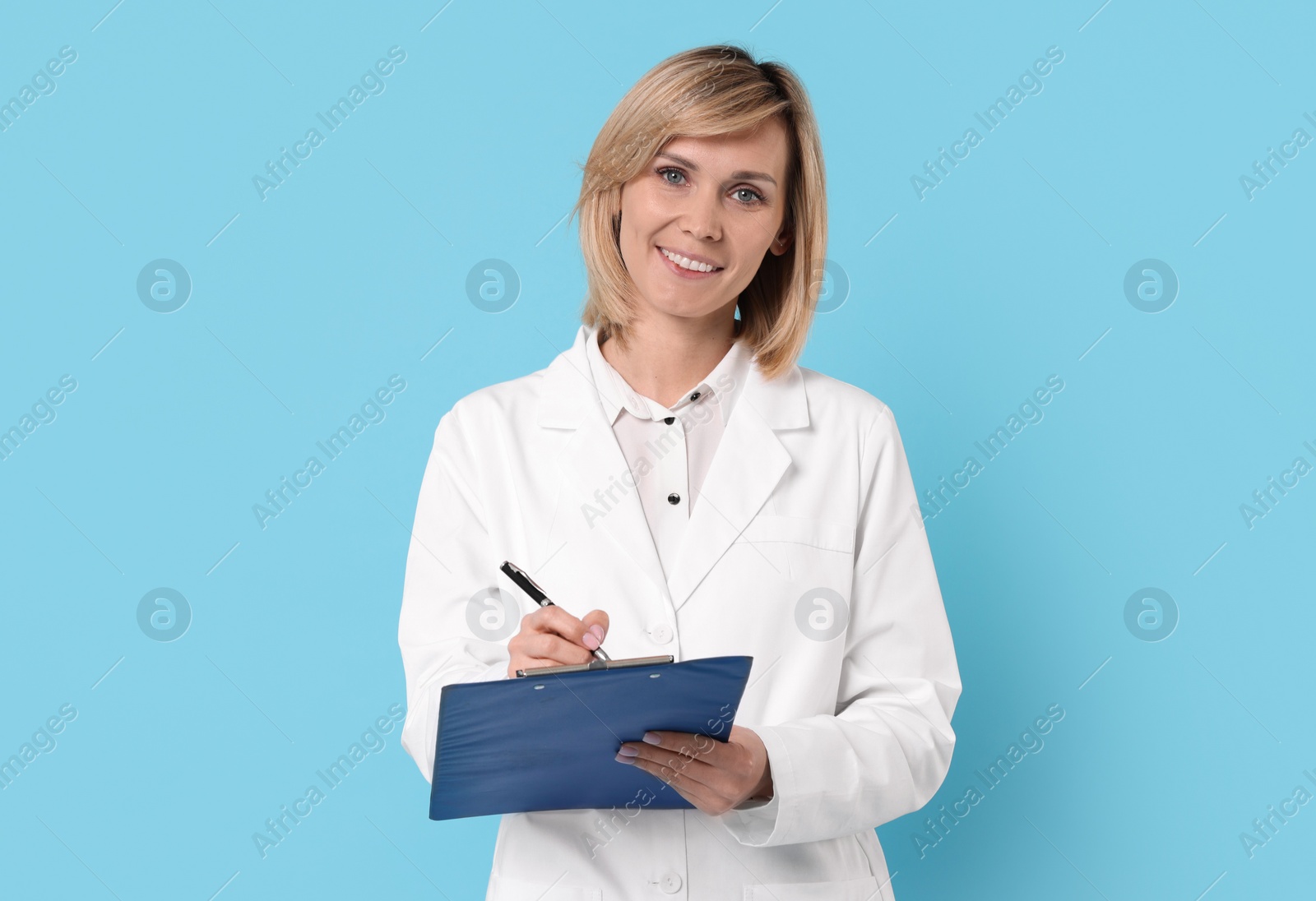 Photo of Smiling doctor with clipboard on light blue background