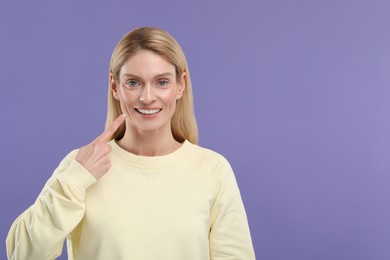 Woman showing her clean teeth and smiling on violet background, space for text