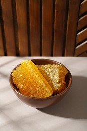 Natural honeycombs in bowl on white table