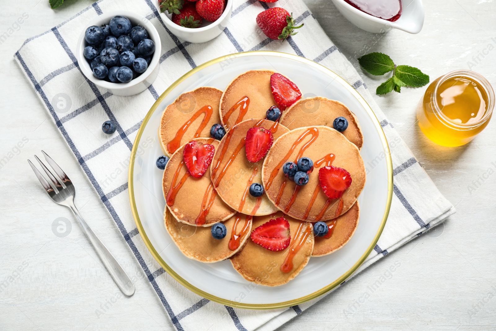 Photo of Tasty pancakes with berries served on light table, flat lay