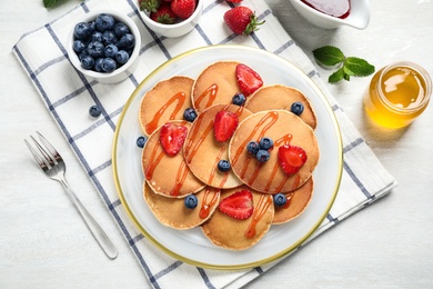 Tasty pancakes with berries served on light table, flat lay