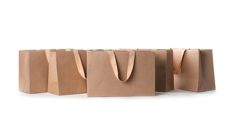 Photo of Paper shopping bags with comfortable handles on white background. Mockup for design