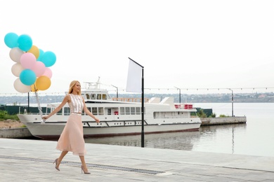 Photo of Beautiful young woman with bunch of balloons outdoors. Space for text