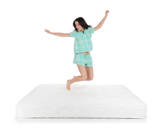 Young woman jumping on mattress against white background