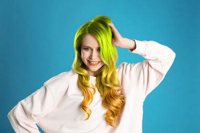 Image of Portrait of young woman with dyed long curly hair on blue background